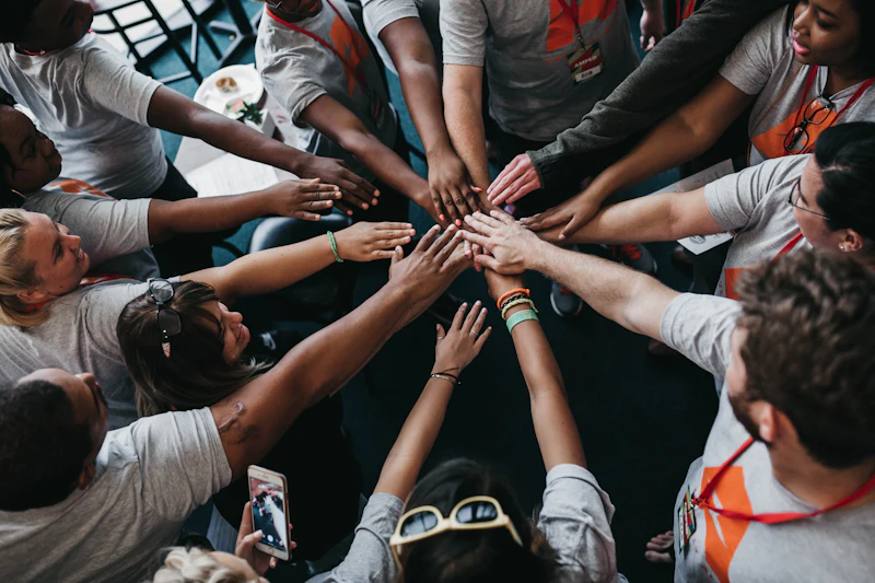 A team of adults putting their hands together in a huddle