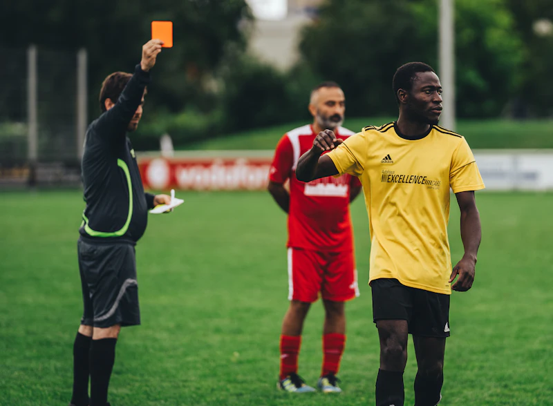 A referee raising a card during an adult soccer match